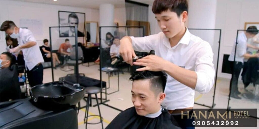 Một thợ cắt tóc đang chuyên nghiệp cắt tóc cho khách hàng, tập trung vào từng chi tiết để tạo kiểu hoàn hảo, thể hiện sự tận tâm của đội ngũ Tóc Nam Đẹp Sáng Tạo Barber Shop.