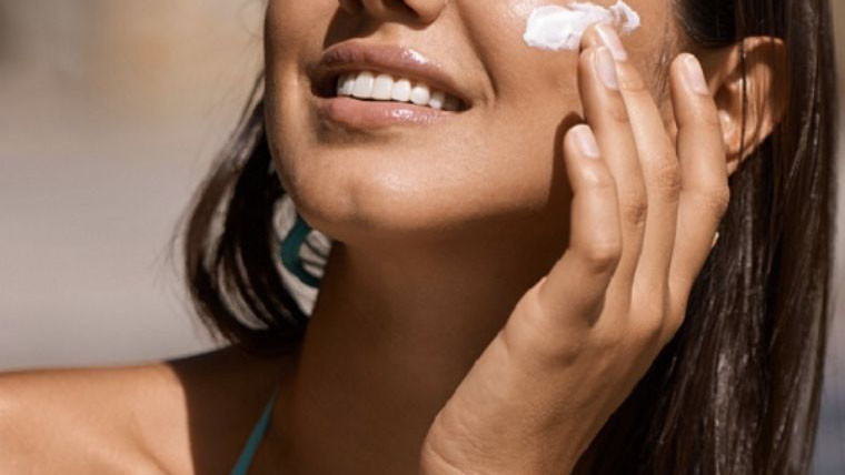 Người phụ nữ đang thoa kem chống nắng lên mặt, minh họa việc lựa chọn kem chống nắng non-comedogenic giúp bảo vệ da và tránh tắc nghẽn lỗ chân lông.