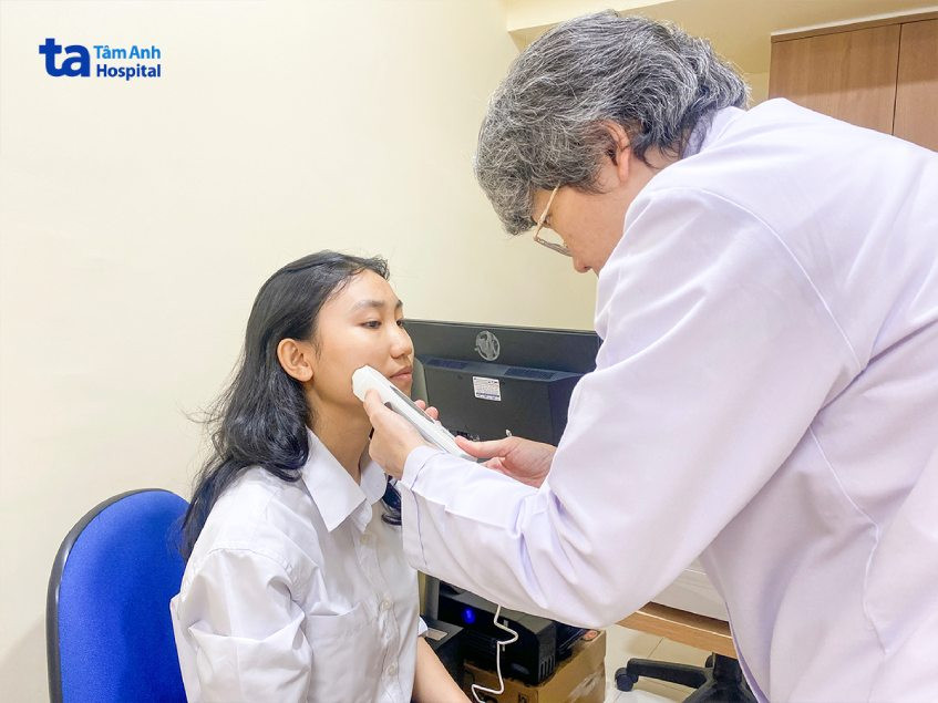 Tiến sĩ Bác sĩ da liễu đang khám và chẩn đoán tình trạng mụn cám cho bệnh nhân