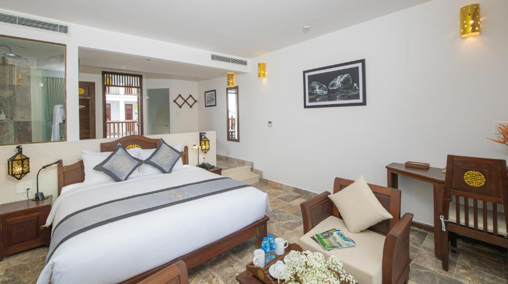 Giường King size thoải mái trong phòng Deluxe Rice Field View tại Hội An Ancient House Village Resort &amp; Spa