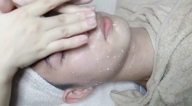 Khách hàng đang thư giãn dưới máy xông hơi mặt chuyên dụng, mở lỗ chân lông và chuẩn bị cho bước tẩy tế bào chết trong chăm sóc da cơ bản tại spa.