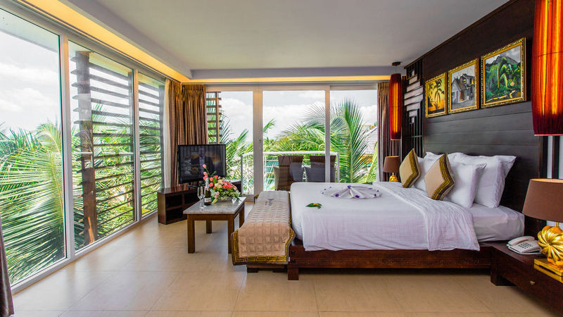 Phòng Premium Deluxe Garden View tại Villa Del Sol Beach Villas &amp; Spa, với khung cửa mở ra khu vườn xanh tươi và nội thất thanh lịch
