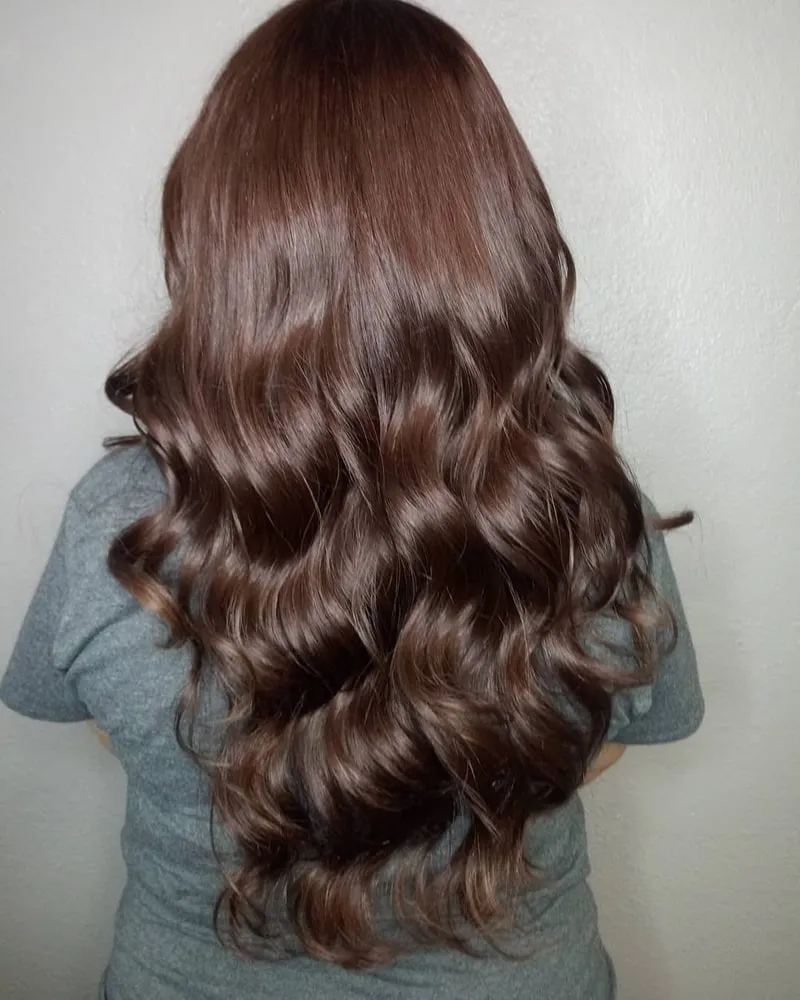 Kỹ thuật viên đang thực hiện nhuộm tóc màu nâu socola trên mái tóc dài