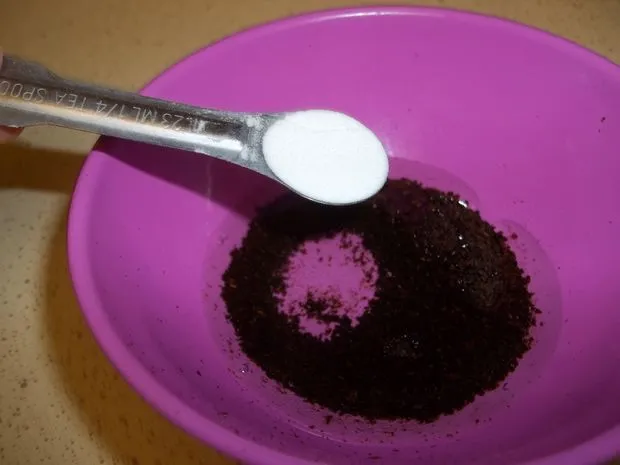 Mô tả cụ thể hạt cà phê và bột cà phê xay đặt bên cạnh một chiếc chén nhỏ