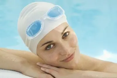Mô tả cụ thể người phụ nữ đang che chắn tóc bằng mũ bơi trước khi xuống hồ bơi
