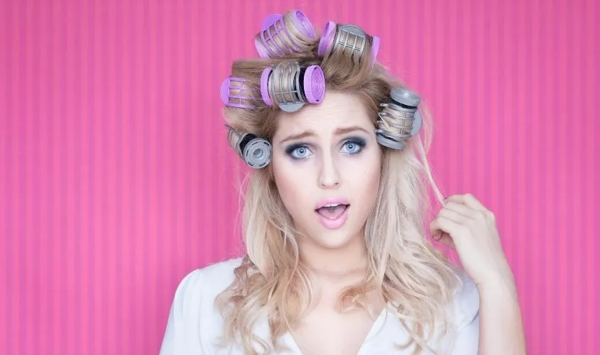 Người phụ nữ đang cuốn tóc vào lô và dùng máy sấy để định hình