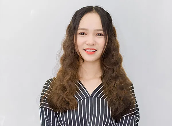 Hình ảnh một người phụ nữ với mái tóc xoăn sóng nước óng ả đang thực hiện thao tác bóp tóc khi xả