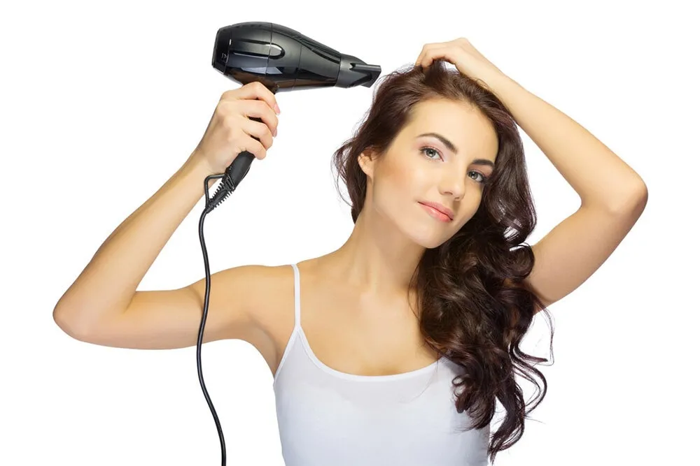 Người phụ nữ đang nhẹ nhàng dùng khăn bông thấm khô tóc sau khi gội để hạn chế tác động nhiệt