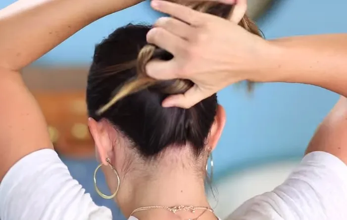 Xoắn toàn bộ tóc lại thành hình búi tóc chuẩn bị cho việc cố định bằng bút chì, minh họa kỹ thuật búi tóc cơ bản