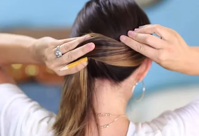 Quấn tóc quanh cây bút chì, tạo hình búi tóc cuộn tròn chắc chắn, một bước quan trọng trong cách búi tóc bằng bút