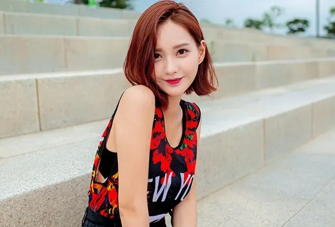 Cô gái với mái tóc dài rẽ ngôi giữa, tóc mái được uốn cong nhẹ ôm sát khuôn mặt, tạo nét quyến rũ