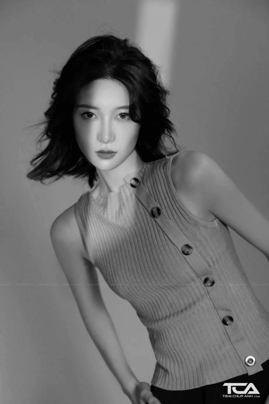 Người mẫu tạo dáng nghiêng đầu, để lộ đường nét cổ thanh thoát và làm nổi bật kiểu tóc bob hiện đại, đây là một tư thế tốt cho cách chụp ảnh tóc ngắn