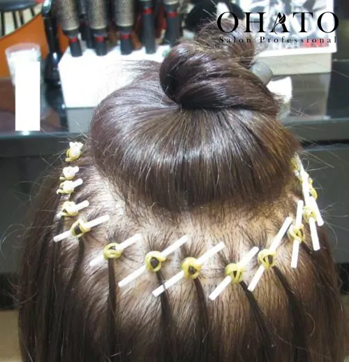 Người phụ nữ với kiểu tóc búi thấp thanh lịch và váy cúp ngực đang tạo dáng trong không gian sang trọng