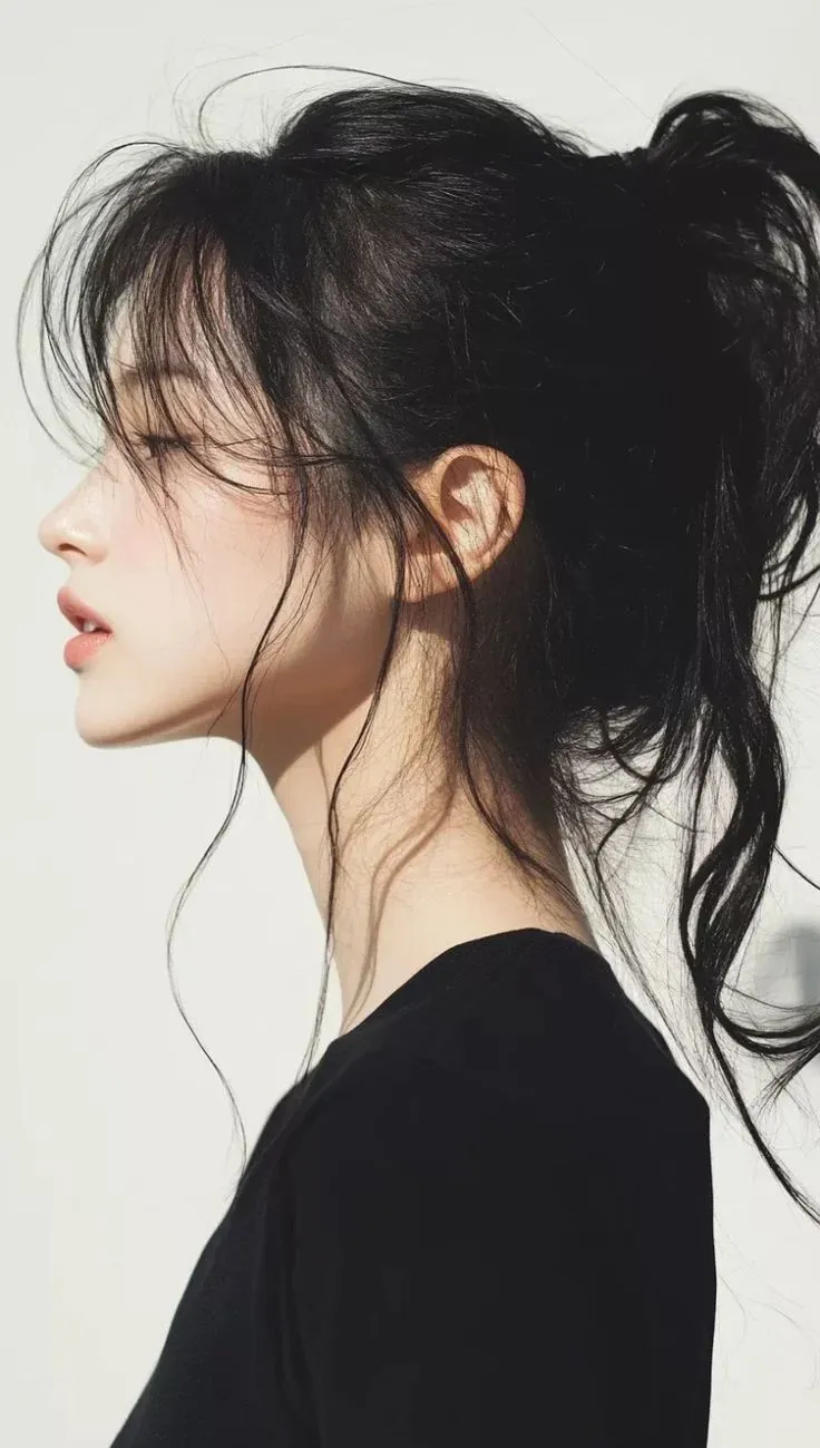 Cô gái tạo kiểu búi tóc thấp nửa đầu (half bun), thể hiện phong cách năng động và thoải mái.