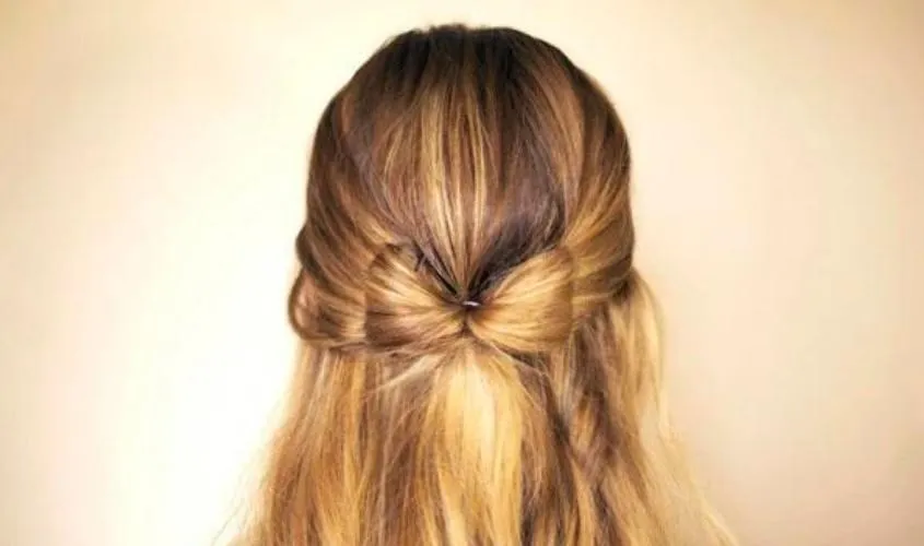 Hình ảnh một bé gái tóc ngắn được buộc tóc cao, sau đó dùng một chiếc nơ to bản để cột và trang trí, tăng thêm vẻ nữ tính.