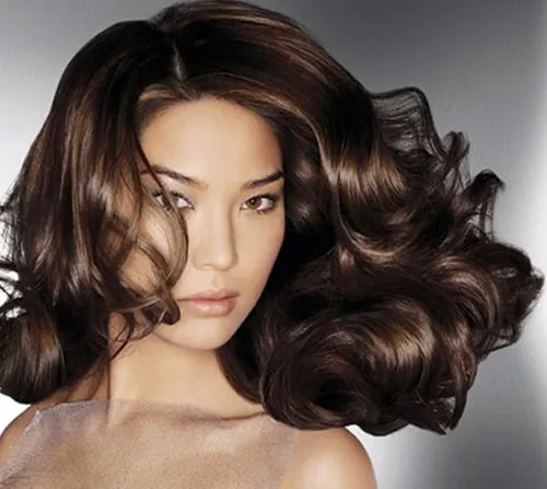 Phụ nữ đang tạo kiểu bóp nhẹ các lọn tóc xoăn để định hình nếp