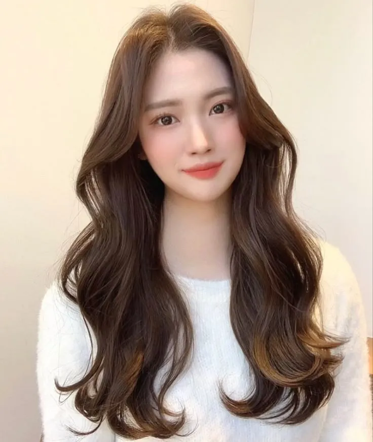 Người mẫu nữ có mái tóc uốn xoăn lơi bồng bềnh, tự nhiên, đang tạo kiểu tóc