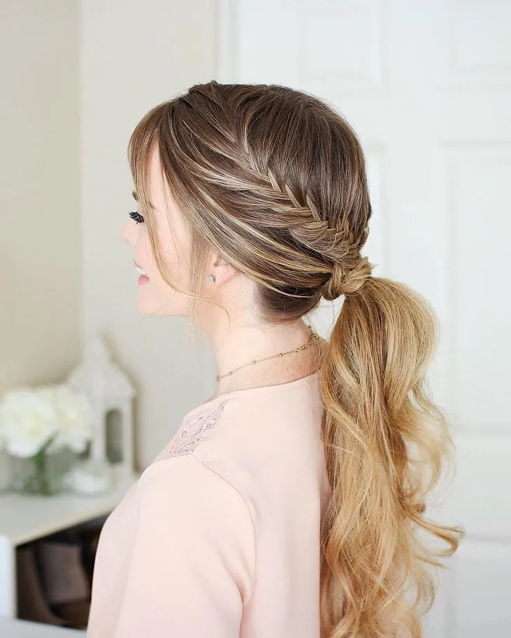 Hình ảnh mái tóc nâu dài được buộc đuôi ngựa thấp, sử dụng phụ kiện nơ đen to bản