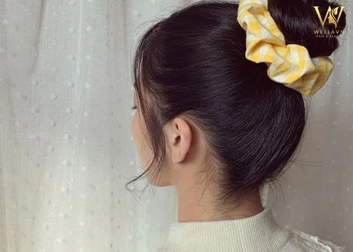 Hình ảnh kiểu búi tóc củ hành thấp, mềm mại, làm nổi bật vẻ nữ tính của học sinh