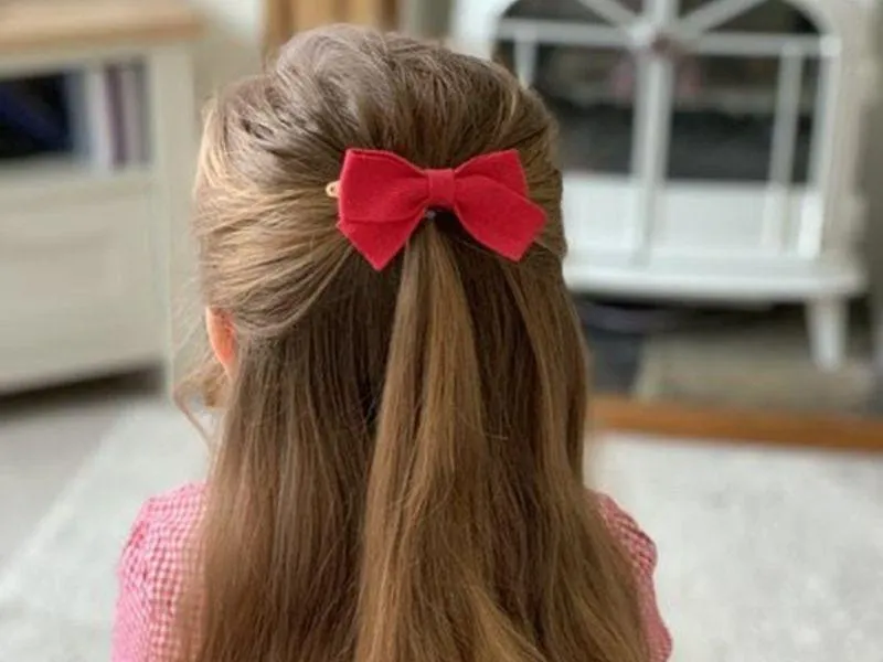 Cảnh bé gái buộc tóc dài nửa đầu với chiếc nơ nhỏ xinh xắn