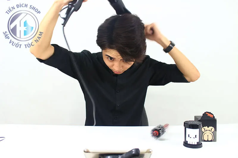 Người mẫu đang dùng lược bán nguyệt để nâng và sấy phồng chân tóc, tạo volume tối đa
