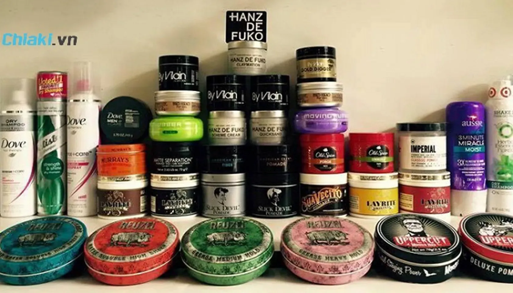 Người đàn ông đang xem xét kỹ lưỡng các loại sáp vuốt tóc khác nhau để chọn sản phẩm phù hợp với chất tóc và kiểu tóc của mình