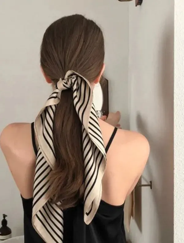 Người phụ nữ đang quấn tóc bằng khăn lụa/satin, một kỹ thuật giữ nếp tóc uốn khi ngủ