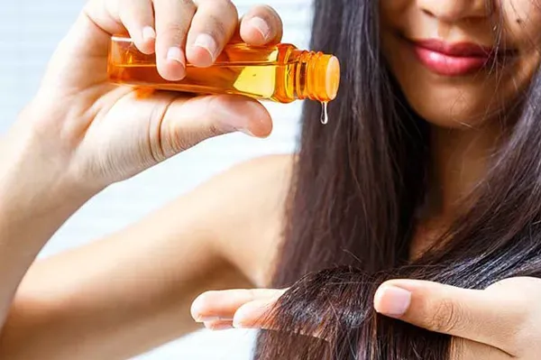 Minh họa việc thoa tinh dầu dưỡng tóc lên phần đuôi tóc để giữ tóc mềm mượt và vào nếp
