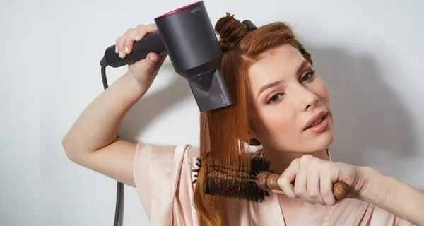 Máy sấy tóc đang được dùng để sấy khô tóc uốn gợn sóng