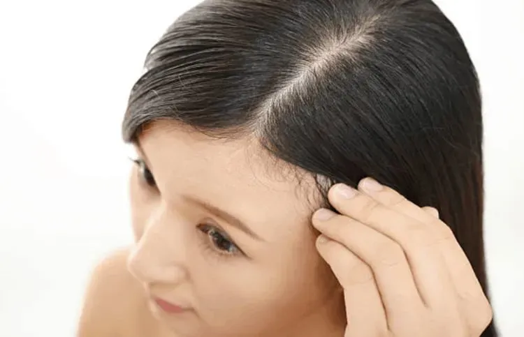 Người phụ nữ đang để tóc khô tự nhiên bằng cách thấm khô bằng khăn