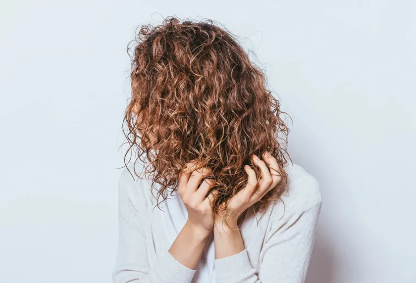 Hình ảnh một mái tóc xoăn xù bị hư tổn đang được quan sát kỹ