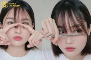 Người phụ nữ đang tỉa đuôi tóc bị chẻ ngọn, minh họa cho việc tỉa tóc định kỳ là cách làm cho tóc dài nhanh nhất