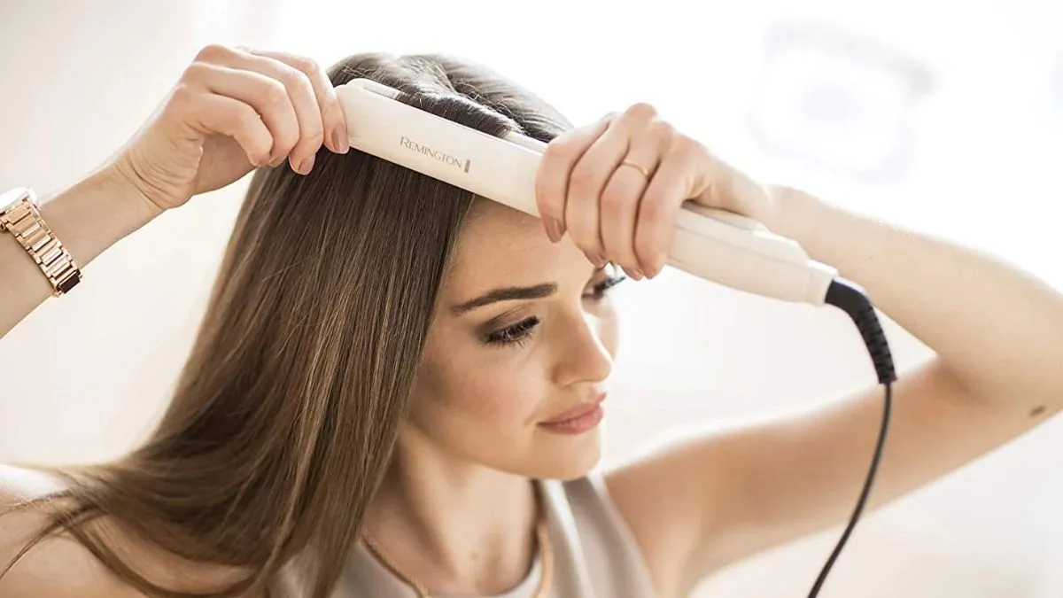 Hình ảnh cận cảnh một chiếc máy ép tóc đang được sử dụng để làm thẳng một lọn tóc