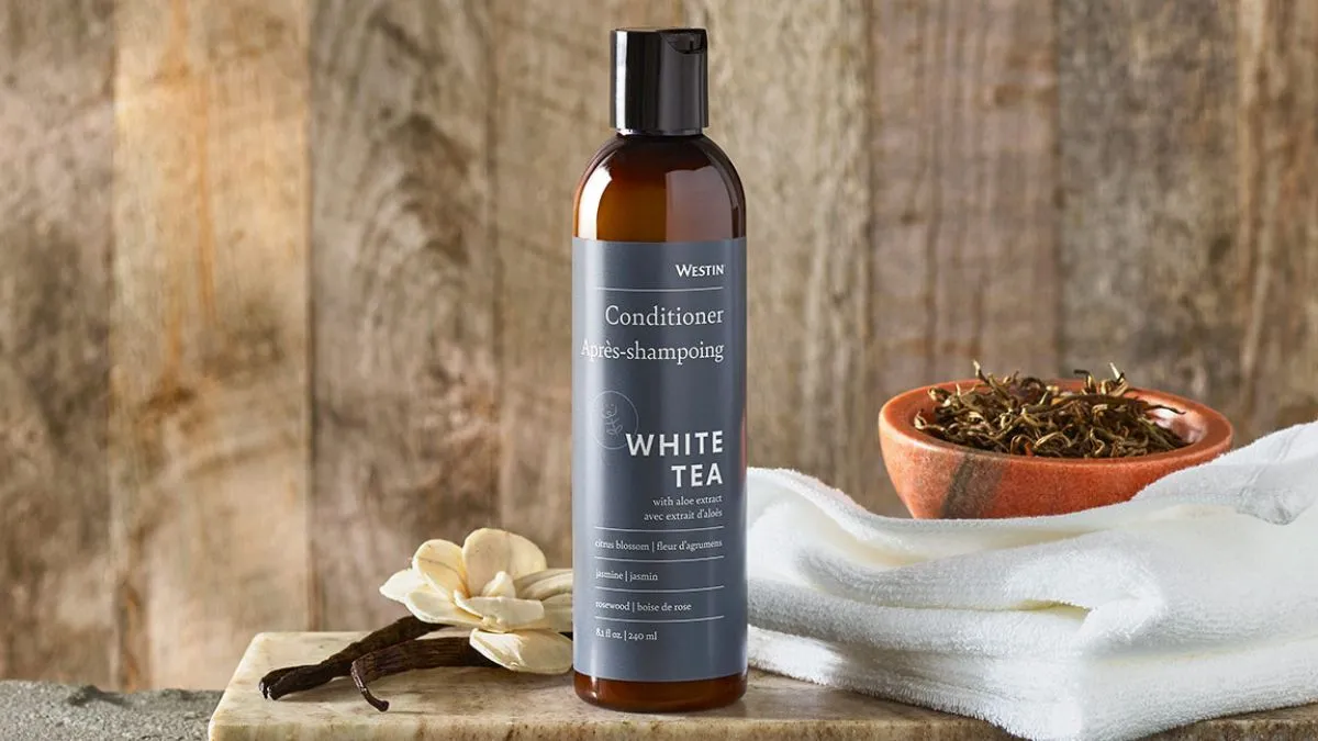 Người phụ nữ thoa dầu xả dưỡng ẩm chuyên sâu lên tóc sau khi gội để làm tóc thẳng tự nhiên tại nhà