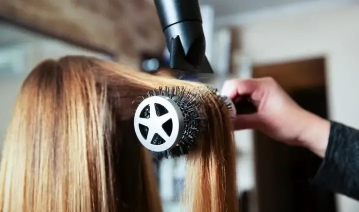 Ảnh chụp cận cảnh kỹ thuật uốn sóng nước nhẹ nhàng cho phần đuôi tóc, sử dụng lược tròn lớn để tạo độ lơi