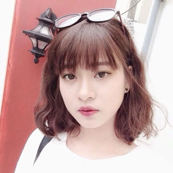 Hình ảnh một lọn tóc ngắn đang được cuốn bằng lô cuốn lớn để tạo kiểu xoăn sóng tự nhiên