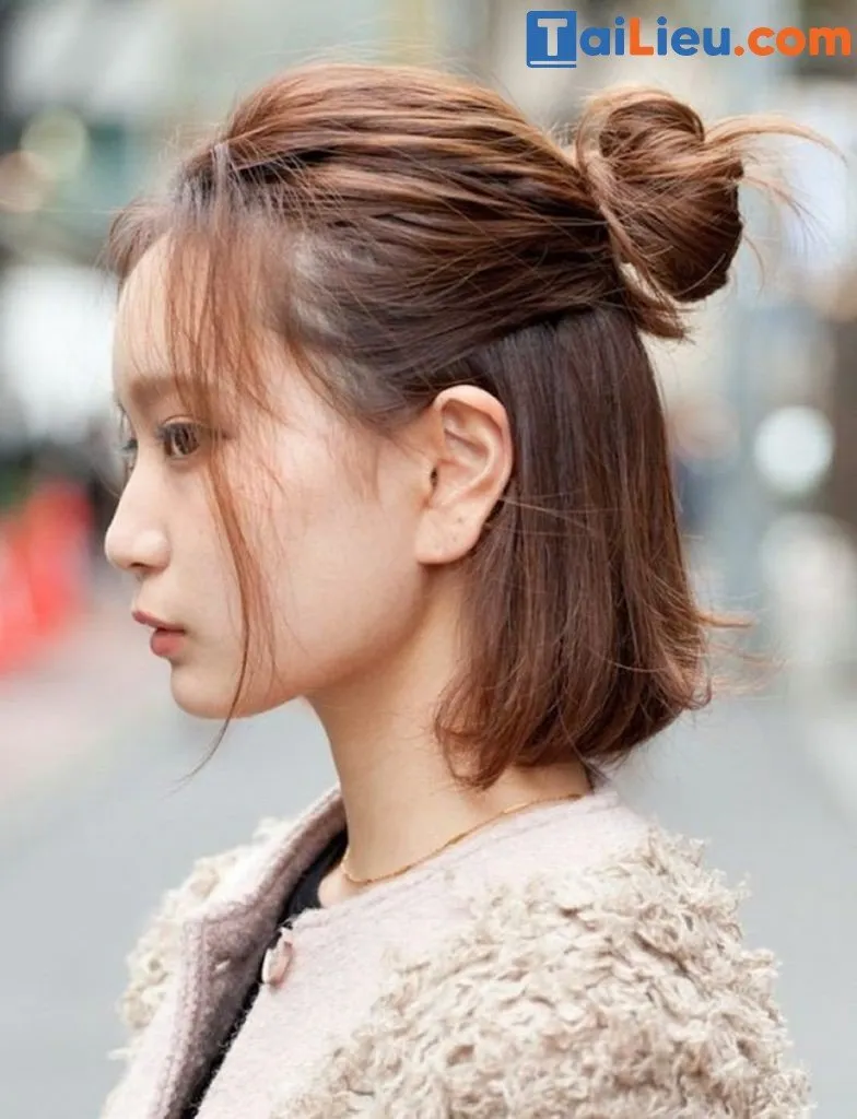 Mô hình khuôn mặt tròn đang thử kiểu tóc búi cao củ tỏi với một vài sợi tóc mai buông lơi tạo sự thon gọn