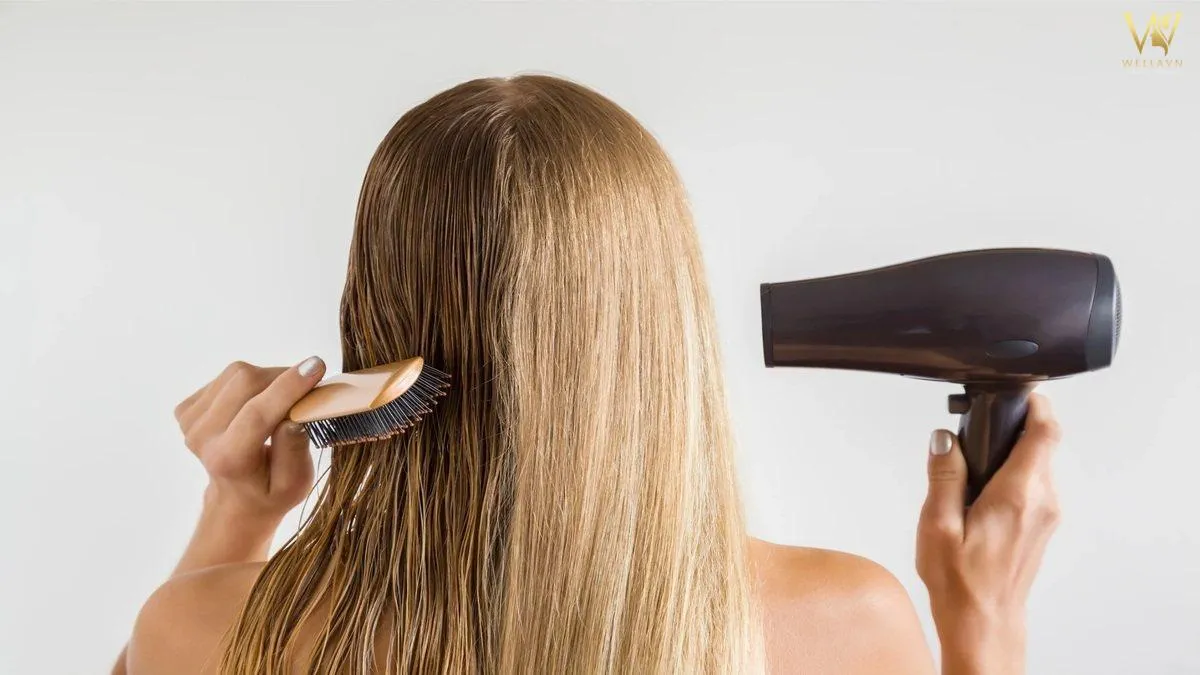 Người mẫu đang thực hiện kỹ thuật sấy cụp đuôi tóc bằng máy sấy và lược tròn tại nhà