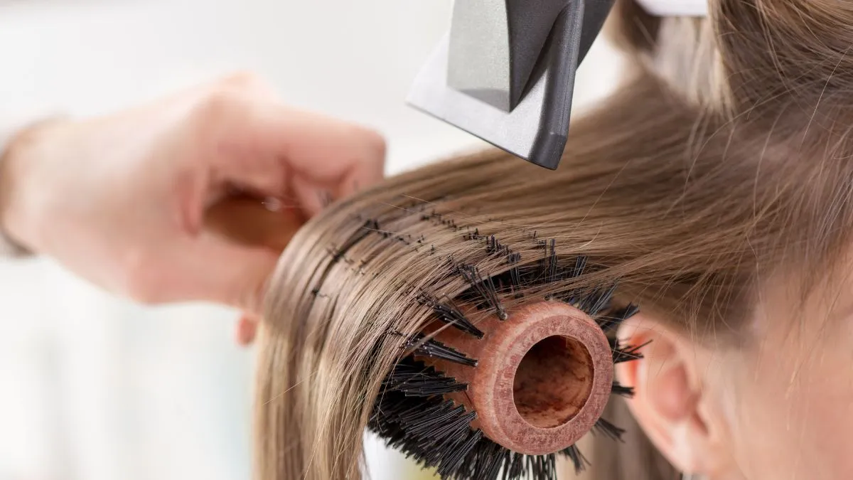 Chuyên gia đang sử dụng máy sấy tóc kết hợp lược tròn để tạo độ phồng và kiểu tóc cúp