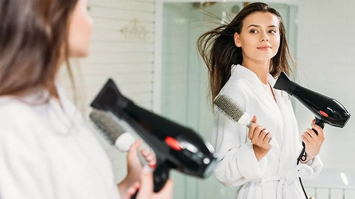 Một chiếc khăn bông mềm được sử dụng để thấm hút nước thừa khỏi mái tóc uốn sau khi gội, đây là bước chuẩn bị quan trọng trước khi sấy tóc để bảo vệ lọn xoăn.