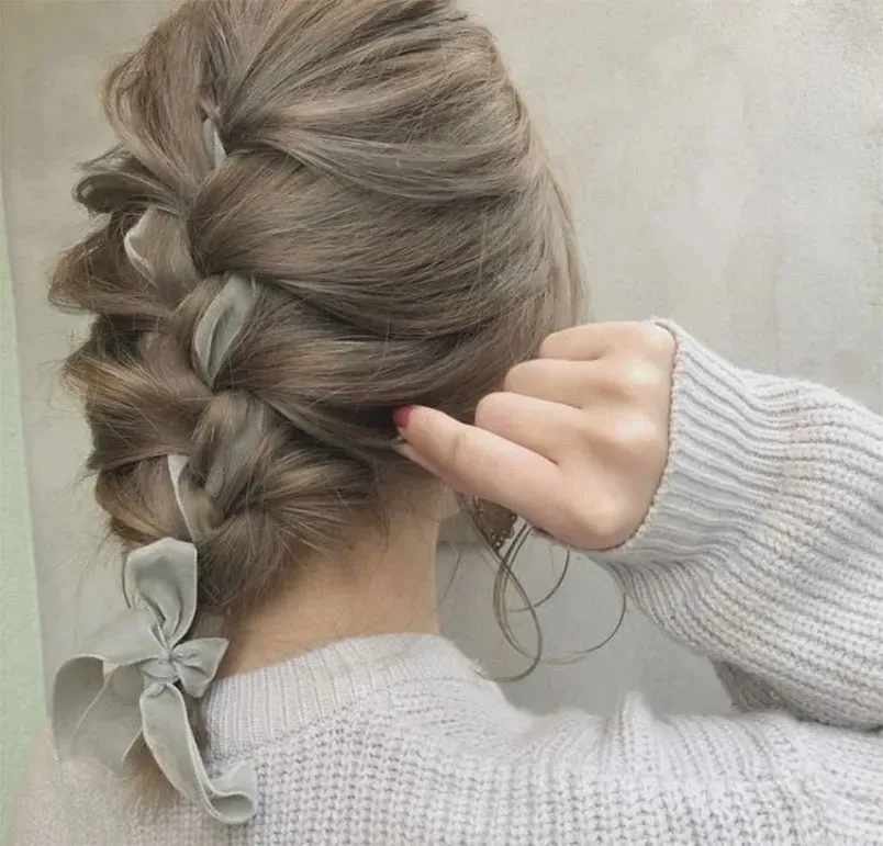 Người mẫu đang tạo kiểu tóc tết xương cá lệch một bên vai, quyến rũ và ấn tượng