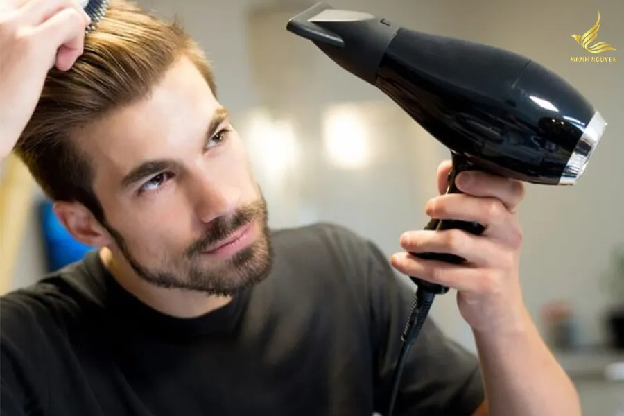 Nam giới đang dùng máy sấy tóc kết hợp với lược để tạo phồng cho tóc