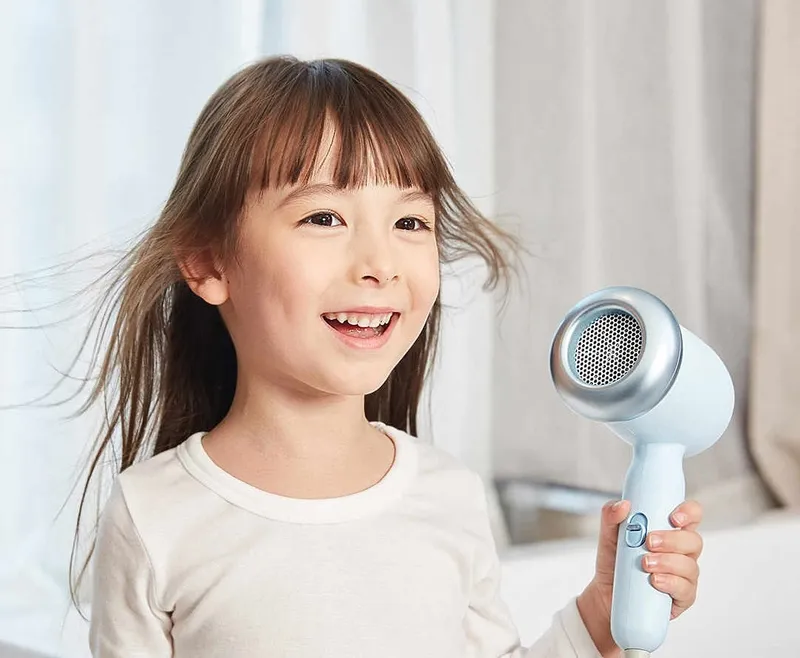 Hình ảnh một người lớn đang cẩn thận sấy tóc cho trẻ nhỏ