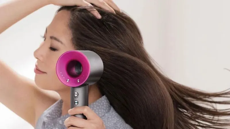 Người phụ nữ sấy thẳng tóc bằng máy sấy và lược mái chèo