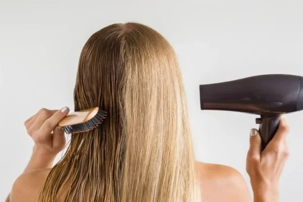 Một phụ nữ đang thoa serum dưỡng tóc lên phần ngọn tóc của mình