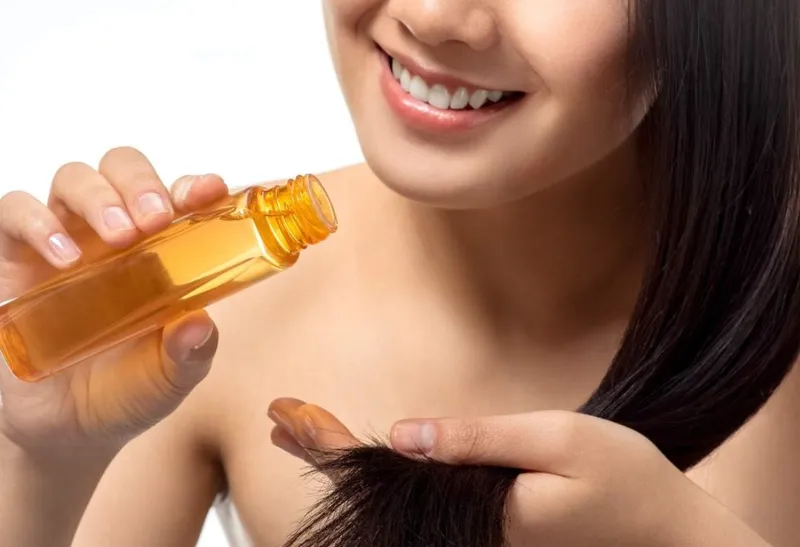 Người mẫu đang xịt sản phẩm bảo vệ nhiệt lên mái tóc khô trước khi tiến hành duỗi thẳng