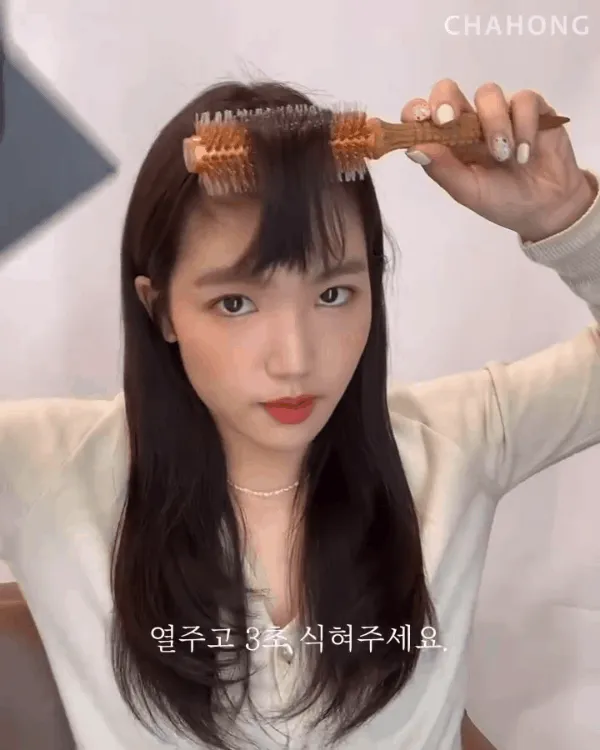 Dùng lược sấy tròn đặt sát chân tóc mái, sấy nóng 1 phút sau đó chuyển sang chế độ mát