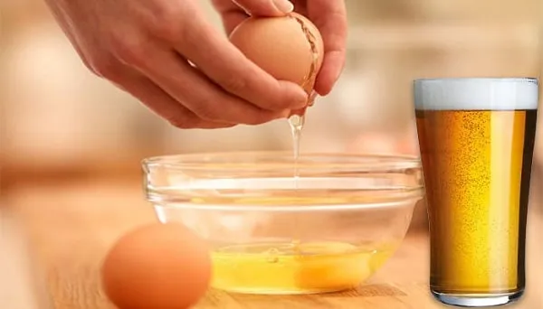 Hình ảnh một người phụ nữ đang cẩn thận xoa bóp mặt nạ ủ tóc làm từ bia và trứng gà lên mái tóc của mình