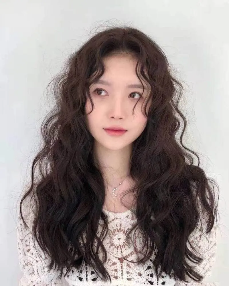 Người phụ nữ đang nhẹ nhàng thoa dầu dưỡng tóc chuyên sâu lên phần ngọn tóc khô xơ