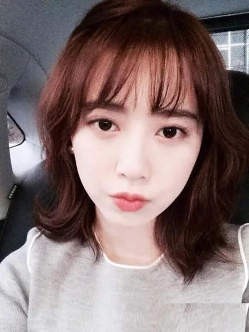 Cô gái mặt dài với kiểu tóc Bob xoăn nhẹ, mái bằng che trán, tạo cảm giác khuôn mặt ngắn hơn